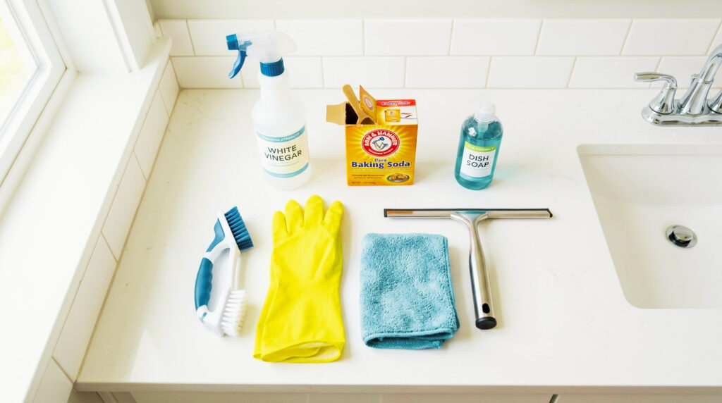 cleaning supplies needed to clean shower tiles including vinegar baking soda grout brush and squeegee